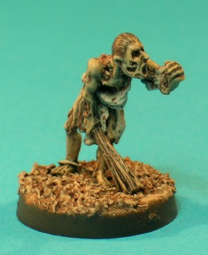 Pose 1, variant A. The Zombie figure represents an animated but decomposing corpse, staggering forwards with his left hand reaching outwards and a wooden club held in his right hand. He wears tattered clothing and has many wounds exposing flesh and bones beneath his skin. This particular variant has slicked-back hair, 2 empty eyesockets, an open mouth and 2 large holes in his right cheek. His head looks straight forwards.