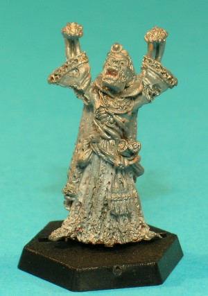 Pose 1, variant C. This Lich variant has a flesh-covered face with many wounds and holes in it, most noticeably on his left cheek and right temple. His left ear is intact, but his right is missing. He has short hair with a centre parting, and wears a jewelled circlet around his head. His mouth is open and he looks upwards and slightly to the right. This variant is easy to mistake for 1D.